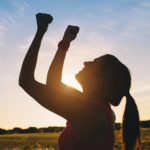 Woman raising arms for celebrating fitness outdoor workout success. Motivation and healthy lifestyle goals concept.